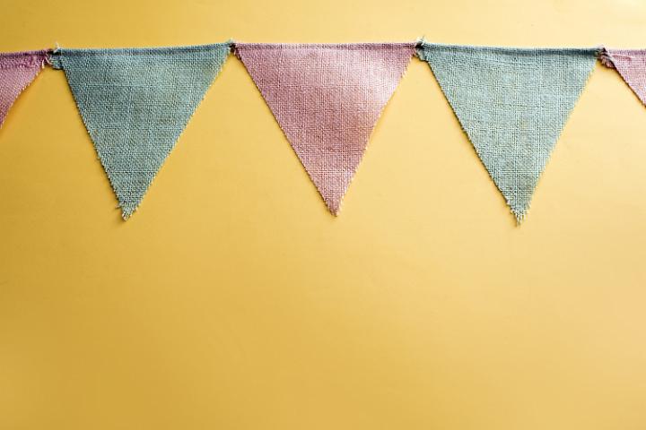 easter_bunting.jpg - Muted green and red Easter bunting decoration with triangular flags strung across a yellow background with copy space