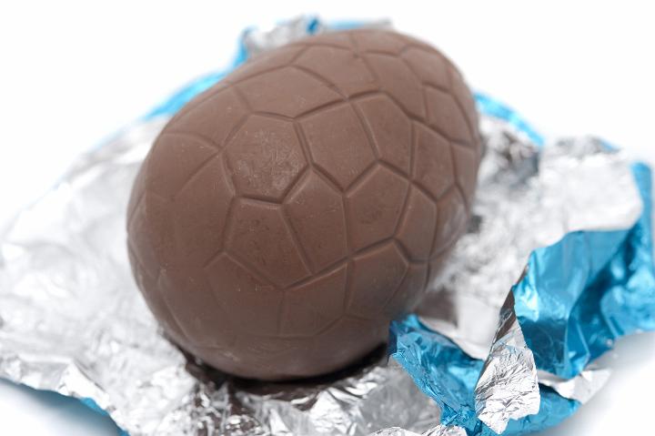 chocolate.jpg - Unwrapped chocolate Easter Egg lying on its colourful blue and silver foil wrapping