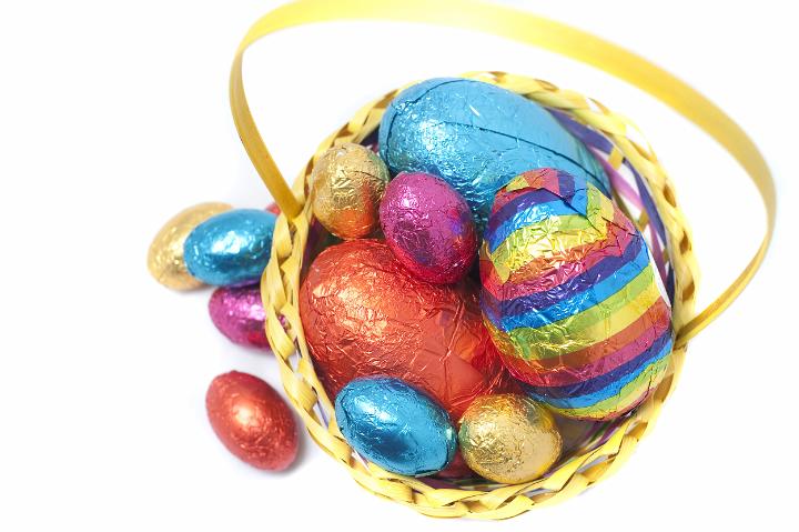 colored_easter_eggs.jpg - High angle view of a decorative basket of different sized colored Easter Eggs in shiny foil wrapping