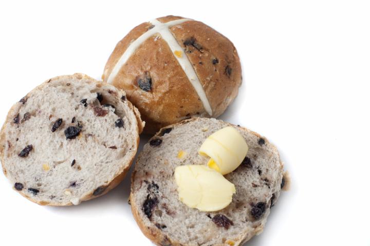 buttered_hot_cross_buns.jpg - Freshly baked sliced and whole Hot Cross Buns with butter over white ready for an Easter celebration, with copy space