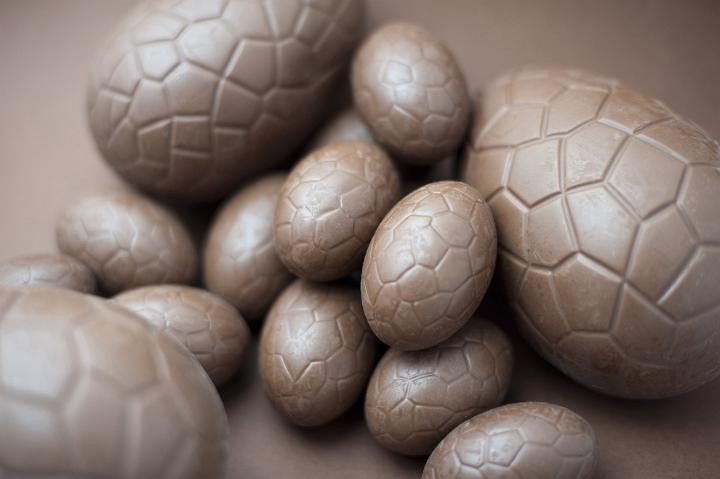 chocolate_eggs.jpg - Assorted unwrapped milk chocolate Easter Eggs of different sizes on a brown background