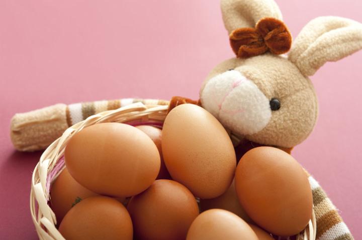 eggs_and_easter_bowl.jpg - Cropped close up on bunch of brown eggs in basket with bunny doll over muted pink background