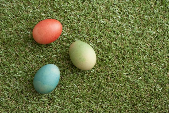 three_easter_eggs.jpg - Three colorful traditional dyed boiled Easter eggs on short neat green spring grass with copy space for your holiday greeting