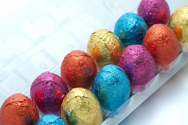 easter_egg_box.jpg - Two rows of colourful foil wrapped Easter eggs standing in a box on a white studio background