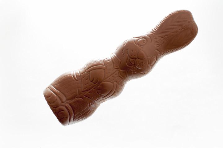 chocolate_easter_rabbit.jpg - Unwrapped chocolate bunny Easter egg lying horizontally through the frame isolated on white with copy space