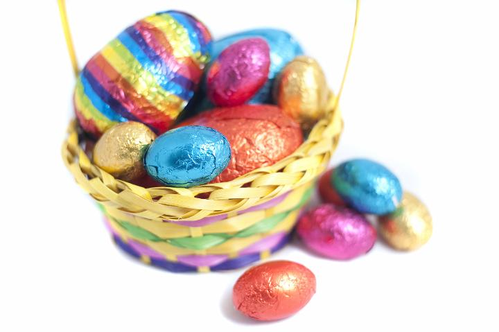 colorful_easter_basket.jpg - Colourful Easter basket filled with multicolour foil wrapped eggs on a white studio background