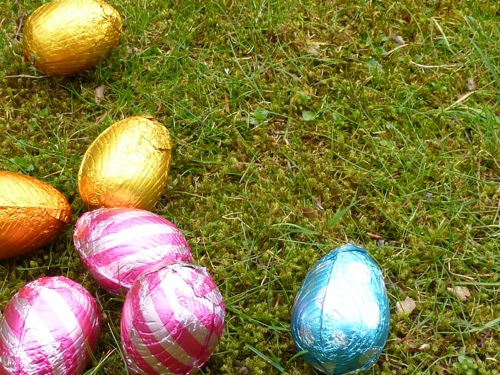 colourful_chocolate_eggs.jpg - Some colourful chocolate eggs in foil sitting on green grass in spring. Easter eggs on the ground with copy space