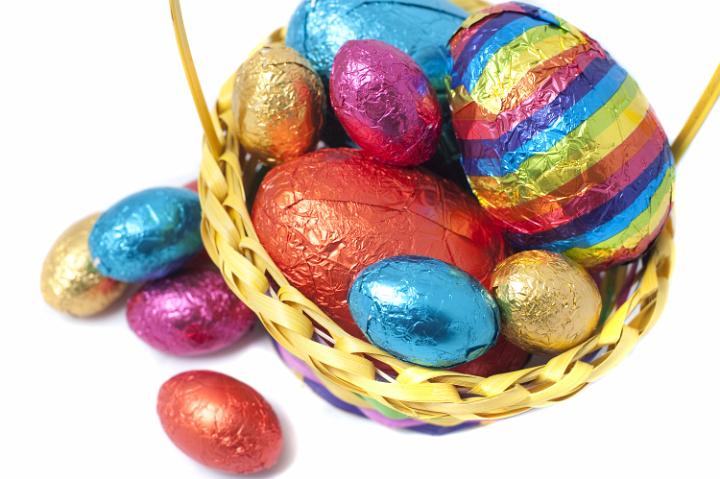 easter_basket_details.jpg - Overhead view of a woven basket full of colourful foil wrapped Easter Eggs in different colours and sizes
