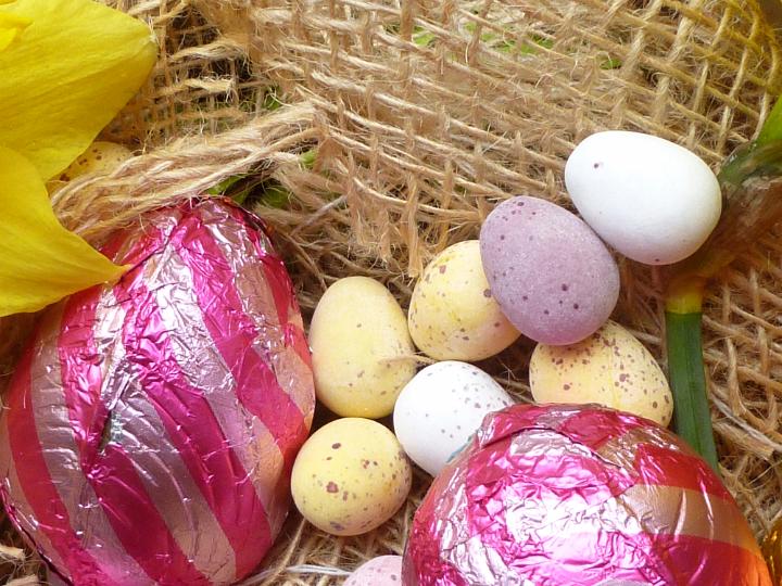 easter_choc_eggs.jpg - Assorted Easter chocolate eggs for the kids in a close up view on sugar-coated mini eggs and colorful foil wrapped ones on hessian