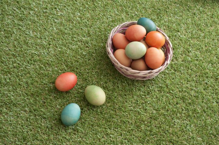easter_egg_basket.jpg - Country Easter with homemade dyed boiled eggs in a wicker basket on green spring grass with three laid to the side and copy space, high angle view