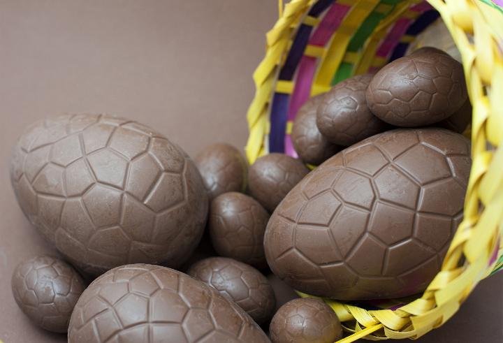 easter_egg_selection.jpg - Easter Egg selection of various sized milk chocolate eggs spilling out of a decorative basket onto a brown background