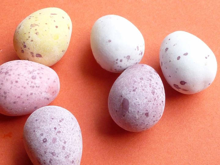mini_easter_eggs.jpg - Mini sugar-coated candy Easter eggs on orange for a traditional holiday celebration in a close up view