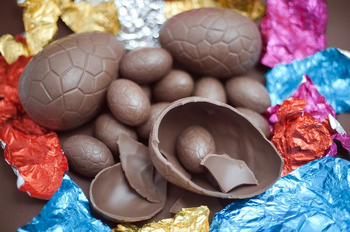 opened_easter_eggs.jpg - Opened chocolate Easter Eggs in a pile amongst their colourful foil wrappers with one large egg broken in half