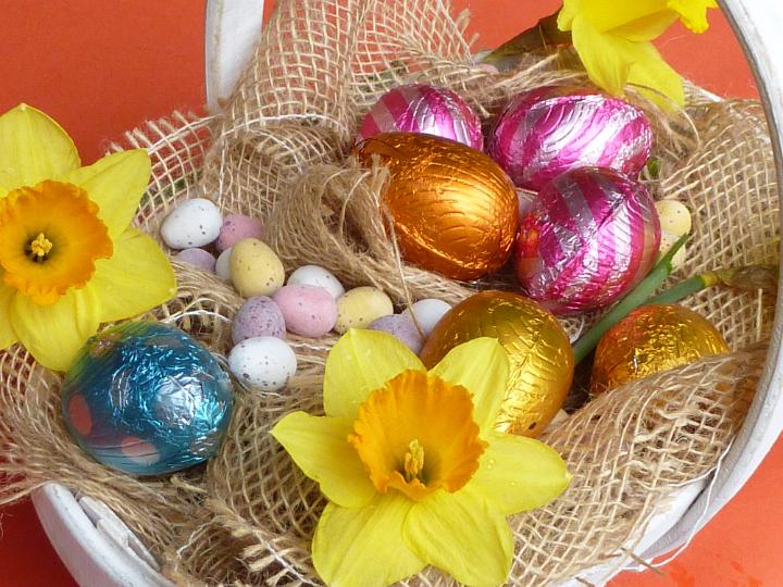 easter_basket_still_life.jpg - Colorful Easter egg and colorful yellow spring daffodil nestling on hessian in a rustic basket viewed from above for celebrating the holiday season