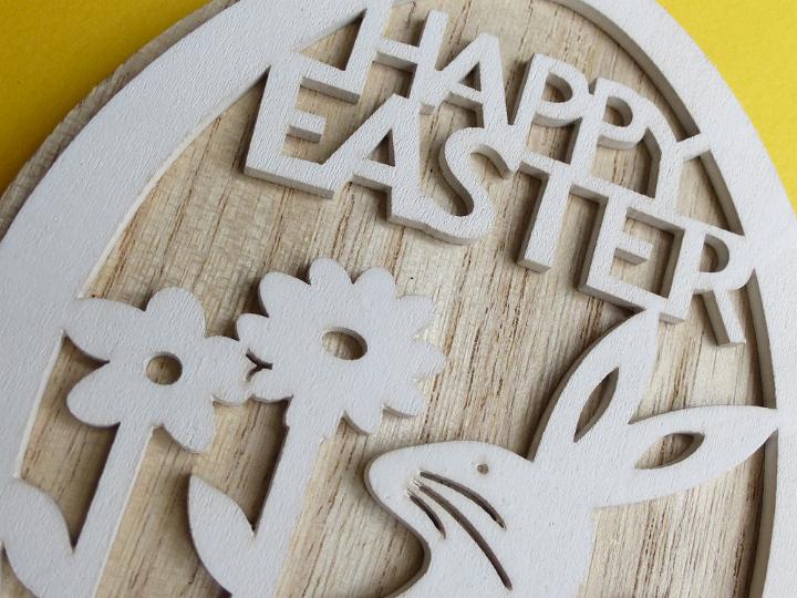 happy_easter_sign.jpg - White decorative Happy Easter sign and a rabbit with flowers carved on wood, viewed in close-up on yellow background